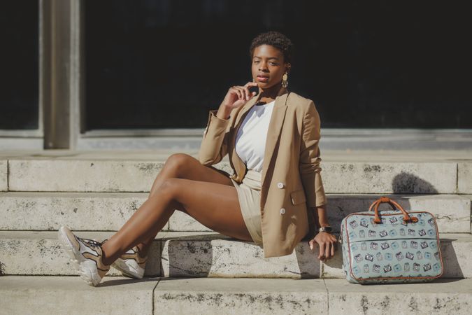 Stylish Black woman with handbag on steps on street