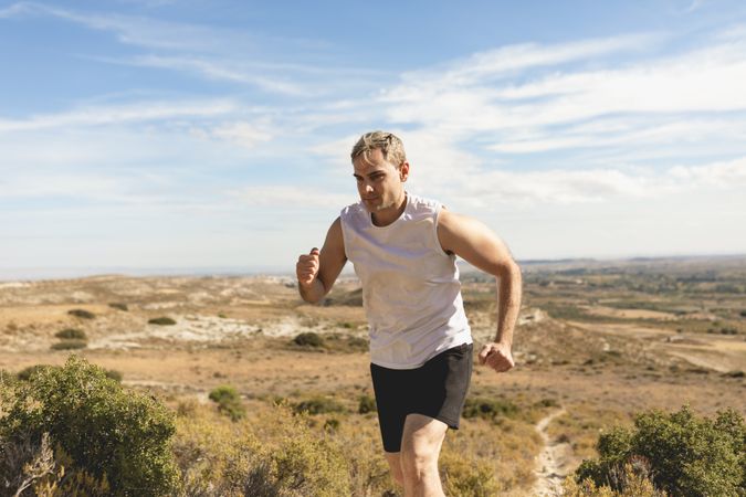 Grey haired male running in vast nature