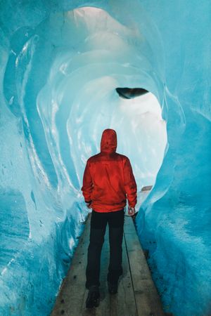 Back view of person in red jacket walking outside of frozen cave
