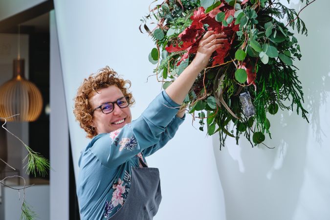 Smiling woman decorating wall with plants