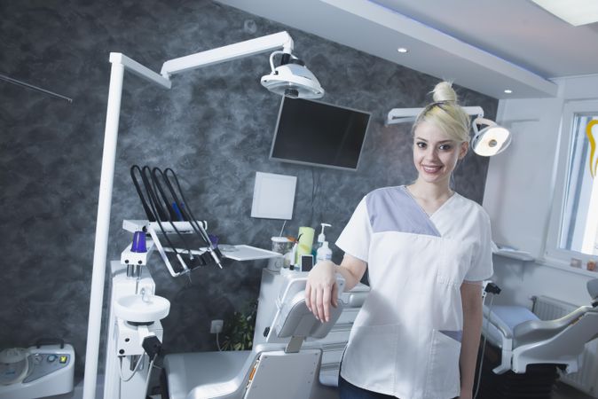Happy blonde dentist surrounded by her equipment