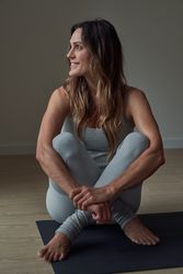Relaxed woman sitting on yoga mat after training