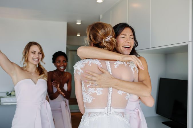 Bridesmaids hugging the bride and smiling