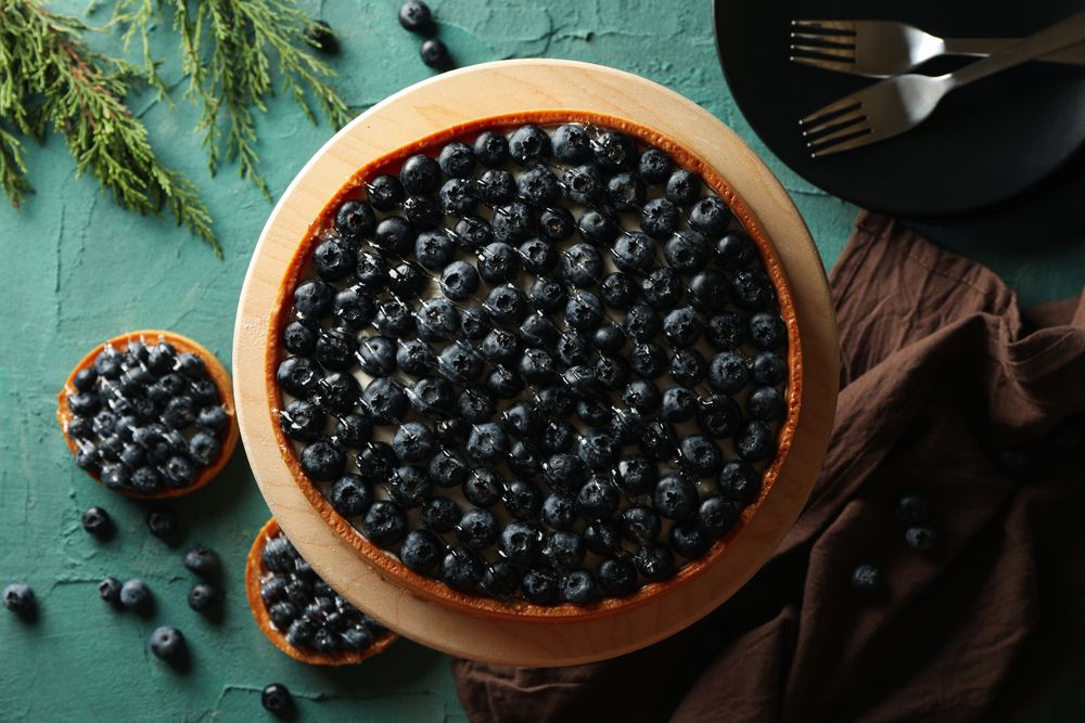Concept of tasty lunch with blueberry pie on green background