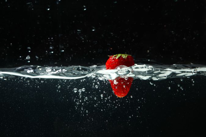 Side view of water on dark background with strawberry