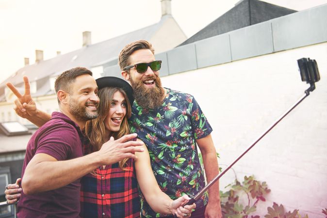 Group of people with selfie stick smiling at the camera on a rooftop