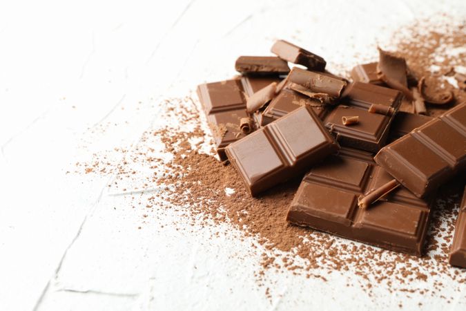 Tasty chocolate and powder on blank background. Sweet food