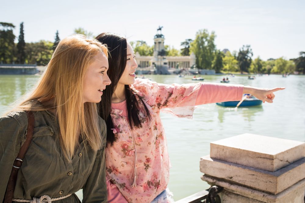 Cheerful multiracial friends sitting on embankment