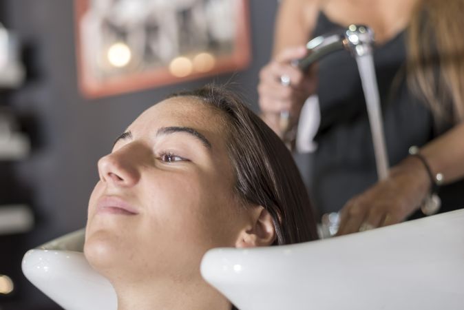 Female sitting with head back in sink at hairdressers having her hair washed