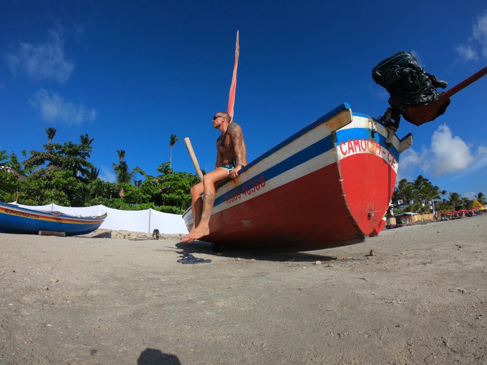 Topless man sitting on boat on sand seashore
