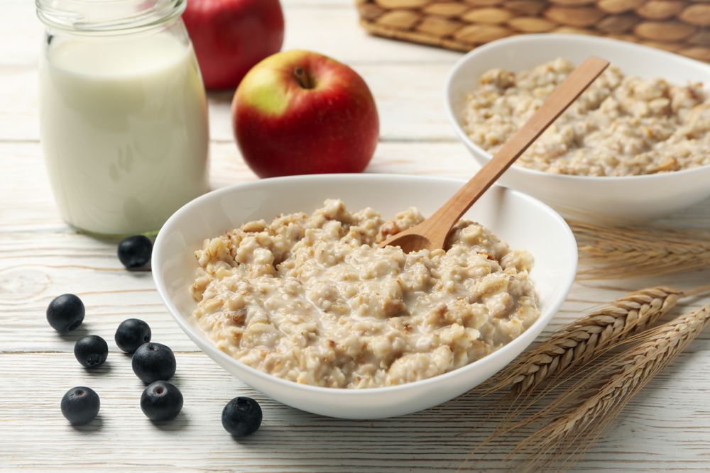 Composition with oatmeal porridge on blank wooden background. Cooking breakfast