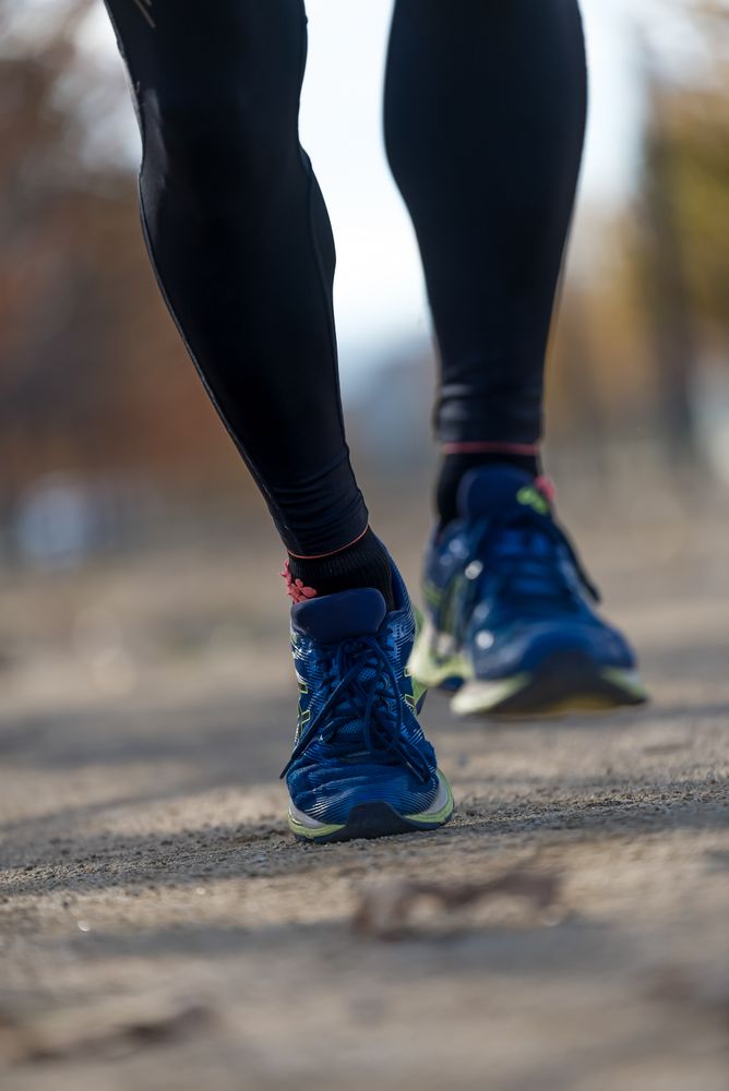 Feet of male in leggings running through park