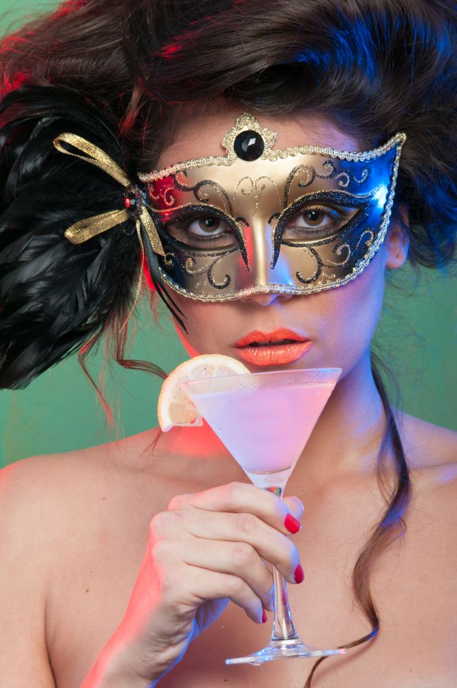 Woman in mask holding glass of drink