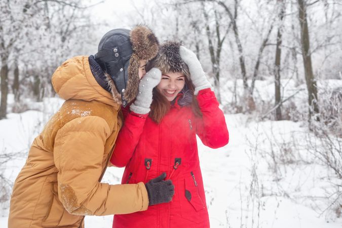 Laughing teenage boy and girl in wintery forest
