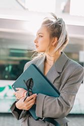 Thoughtful woman with ponytail hair holding tablet and waiting train
