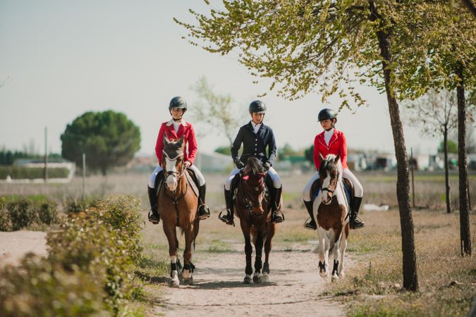 Young horse riders on pathway in nature