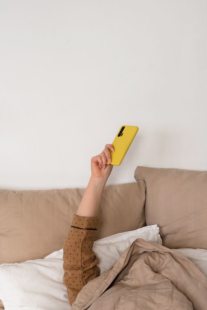 Hand holding smartphone in bed