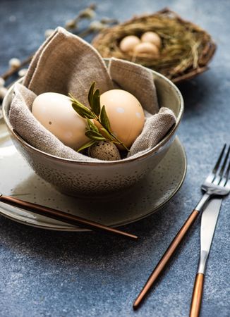 Easter holiday table setting with bowl of eggs and branch