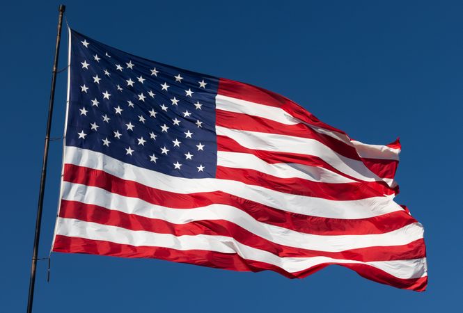 American Flag Waving In Wind Against a Deep Blue Sky.