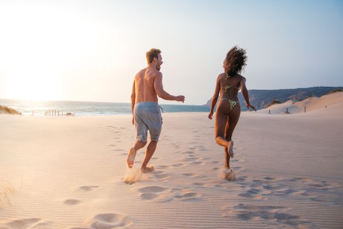 Happy couple running on tropical romantic beach