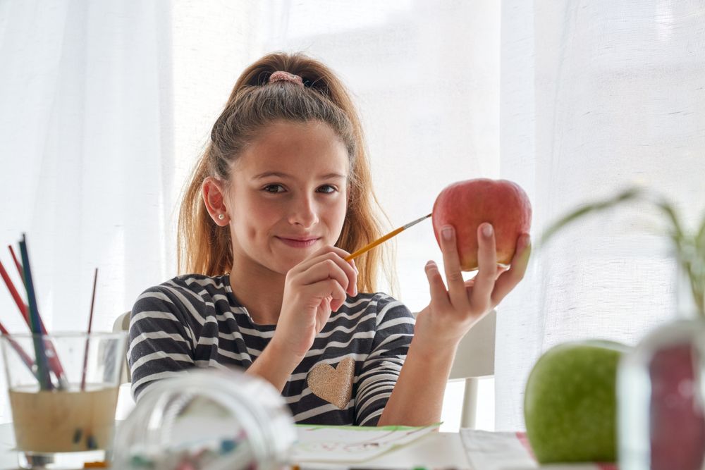 Positive girl painting on apple