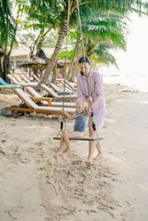 Happy child swinging with mother support while resting on ocean beach