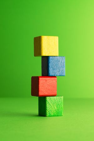 Colorful wooden blocks stacked over green background