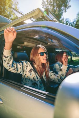 Happy woman raising arms and dancing inside of car