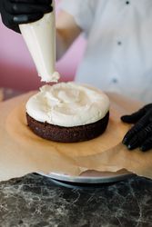 Person putting icing on cake