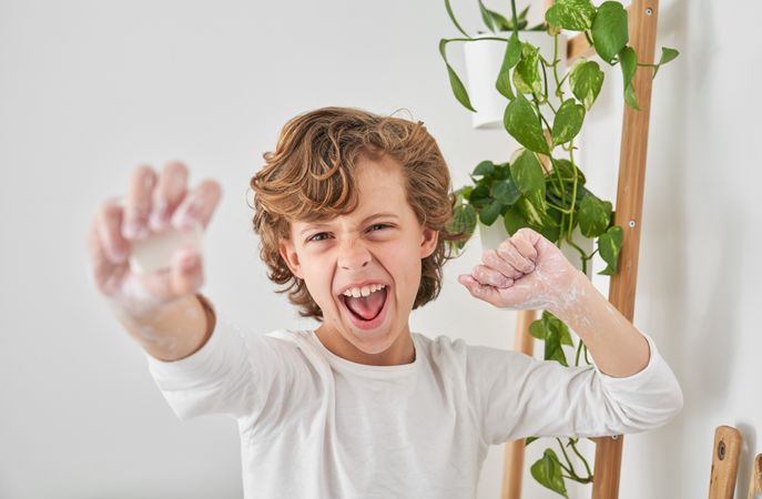 Excited boy reaching out hand with soap