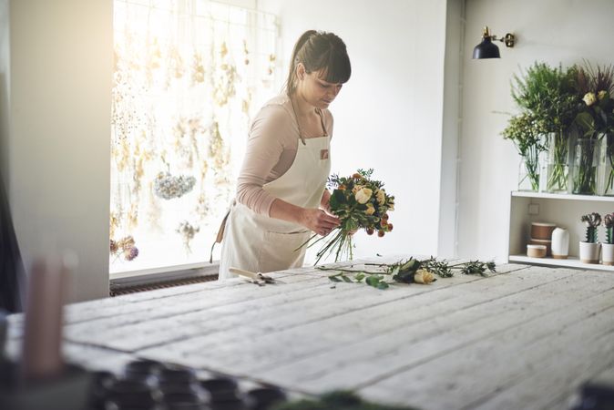 Florist preparing flowers for a bouquet in her shop