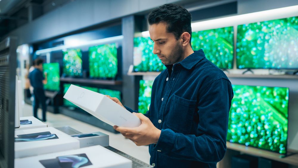 Young Man Shopping for a Tablet Computer in a Home Electronics Store.
