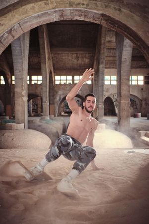 Shirtless dancer training break dance in forgotten building