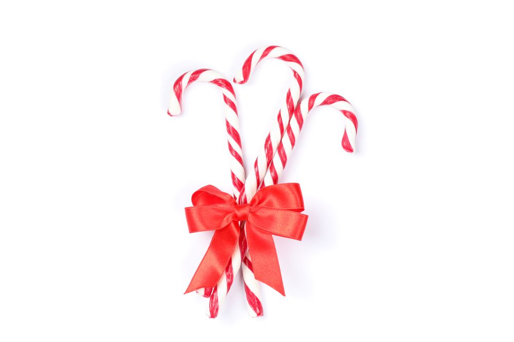 Sweet candy canes with bow isolated on plain background