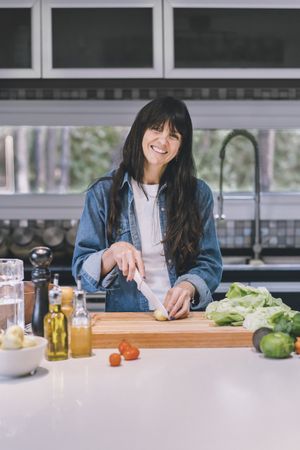 Portrait of a housewife cooking while looking at camera in the kitchen at home