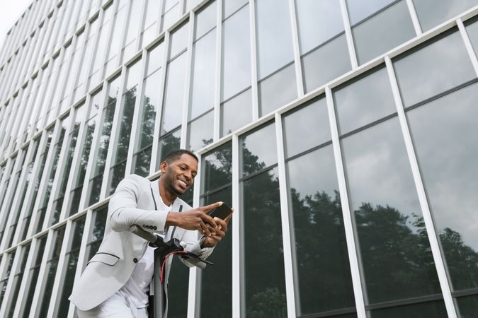 Smiling Black man riding scooter and speaking on smartphone