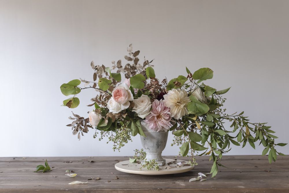 Composition of flowers and plants in vintage vase on board