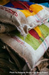 Close up of three colorful burlap bags holding raw coffee beans 0KMxV4