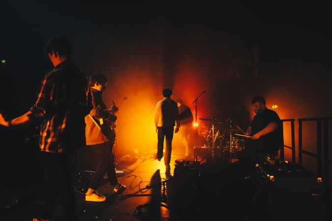 Warm orange spotlight illuminating live rock band performing on stage
