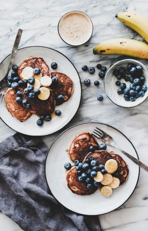 Breakfast banana pancakes with blueberry, honey and coffee, top view, vertical