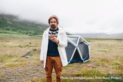 Man waking up from tent with coffee 4MOez0
