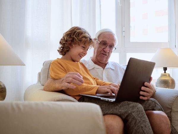 Happy grandfather and grandson watching video on netbook