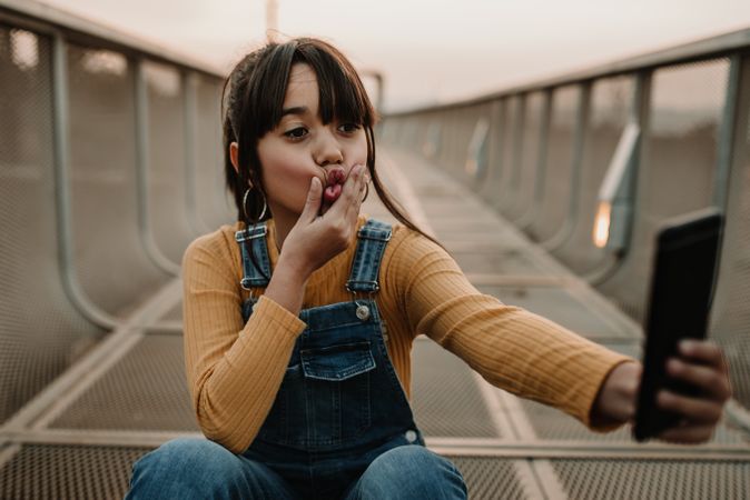 Funny girl taking selfie on smartphone on walkway