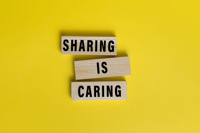 sharing is caring words text on wooden blocks isolated on yellow background