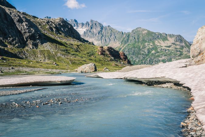 Shallow river flowing along rocky shore in bright day
