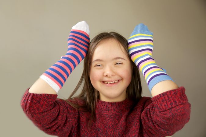Happy young child wearing striped socks on her hands