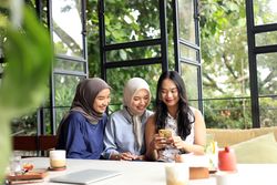 Cheerful and Asian Female Friends are Enjoying Eating food, Drinking, and Hanging Out at a Restaurant or Cafe