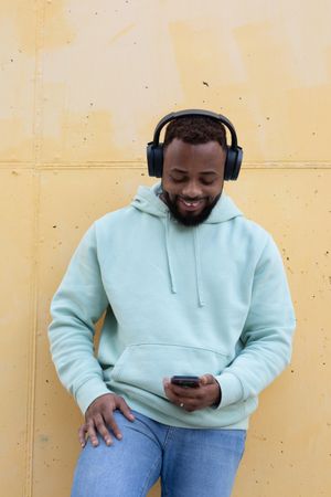 Happy Black man with headphones and smartphone