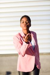 Front view of female in modern business suit making kissing face outside