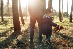 Father and son in a face mask walking in the woods